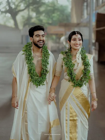 A joyful shot of the newly married couple walking hand-in-hand through the corridors of the Guruvayur temple, their happiness lighting up the frame.