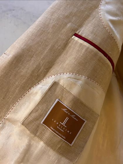 The interior of a custom linen blazer, showing the partial silk lining and our signature brand label.