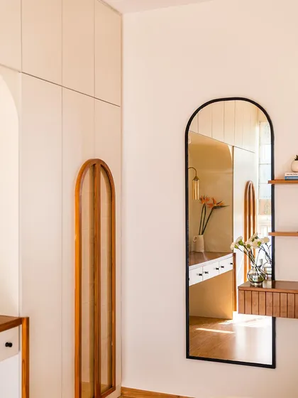 The arched mirror in this bedroom reflects the arched cane details on the wardrobe, creating a harmonious and elegant design story.