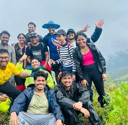 A group selfie on a lush green mountain, with everyone smiling and having fun. These are the candid moments that make our trips special.