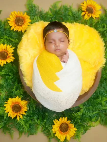 Your little one is a ray of sunshine, and we capture that joy in our newborn sessions. Here, a peacefully sleeping baby is nestled in a cozy, sunflower-themed setup, creating a warm, vibrant, and utterly adorable portrait.