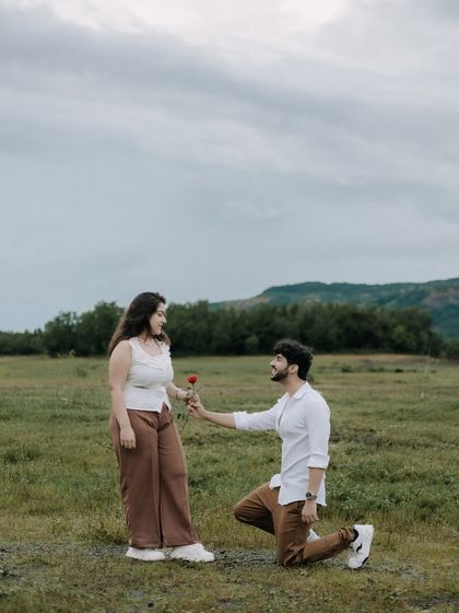 A classic proposal pose, with the groom on one knee offering a rose. Set against a wide-open field and distant hills, this shot feels both intimate and grand.