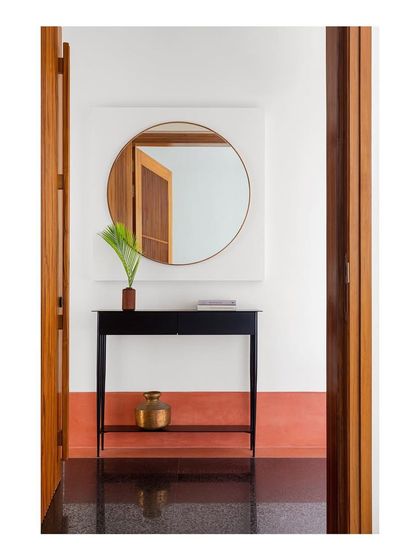 This entryway moment, which was published in a magazine, shows how I use simple forms and strong material contrasts. The slim black console table stands against a white wall, framed by warm teak doorways.