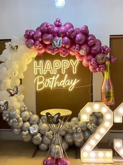 A chic 23rd birthday ring setup with magenta, white, and silver balloons, butterfly accents, a neon sign, and marquee numbers.