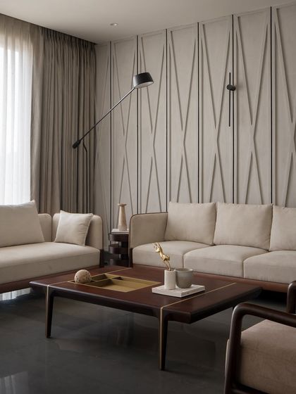 The upper-floor living area, with its clean lines and material integrity. The textured wall, neutral sofas, and custom wood furniture create a space that is calm and sophisticated.