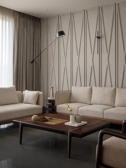 The upper-floor living area, with its clean lines and material integrity. The textured wall, neutral sofas, and custom wood furniture create a space that is calm and sophisticated.