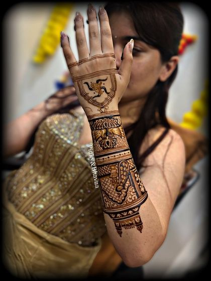A close up of the back of the hand, featuring a Swastik symbol for good luck and prosperity, surrounded by traditional patterns.