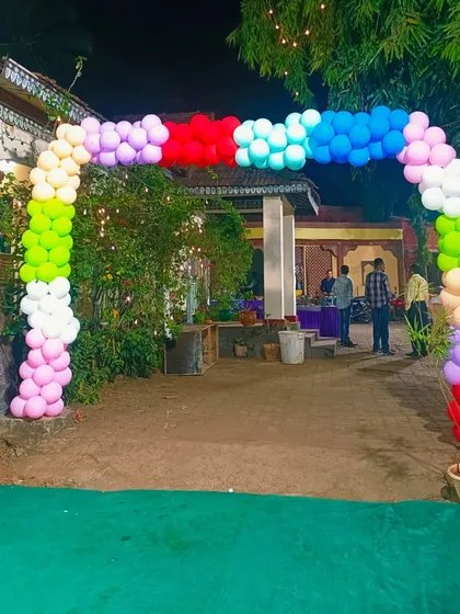A multi-colored balloon arch creates a festive entrance for an outdoor or garden party.