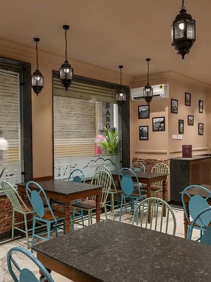 Another view of the dining area at Shiv Mishthan Bhandar, showing the traditional lanterns and framed pictures. The design aims to create a nostalgic yet comfortable dining atmosphere.