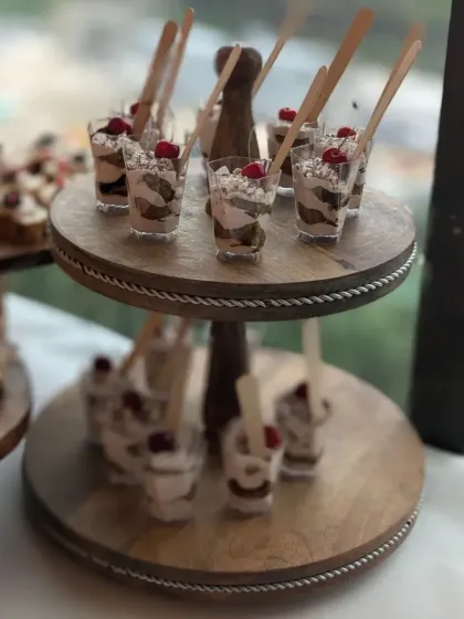 Tiramisu cups served on a rustic wooden two-tiered stand. Each cup is a perfect individual portion of this beloved Italian dessert, ideal for easy serving at events.