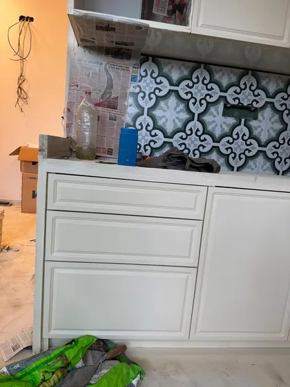 A close-up of the shaker-style cabinet drawers and the intricate backsplash tiles during the kitchen installation.
