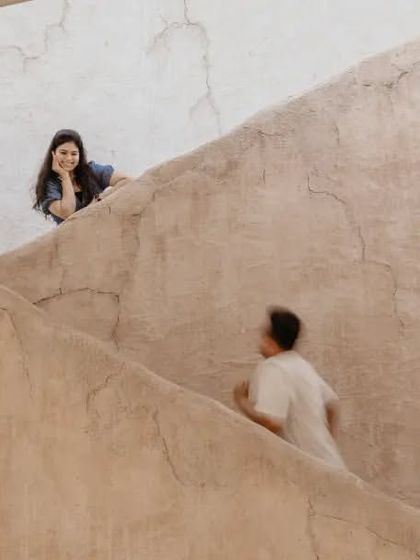 A creative composition showing him walking up a rustic staircase towards her in Dubai. This image uses the location's architecture to tell a story of pursuit and connection.