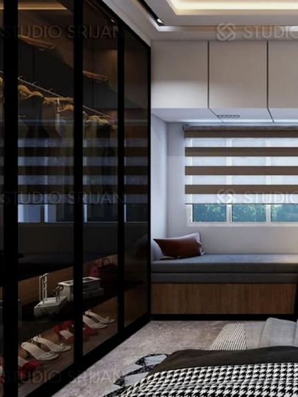 A sleek and modern walk-in closet with black-framed, smoked glass doors. A cozy, cushioned window seat is built in, providing a comfortable spot to get ready.