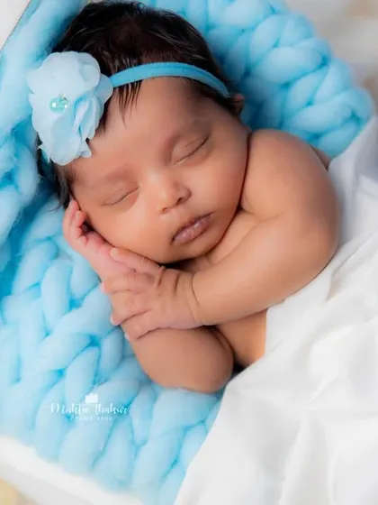 A close-up of a sweet 20-day-old angel, sleeping peacefully on a soft blue blanket in our moon-and-stars setup.