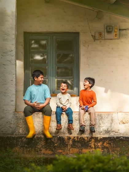 The sound of shared laughter between brothers is pure music. This candid moment captures the easy joy and friendship that defines siblinghood, set against a rustic, sunlit backdrop.