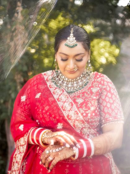 A quiet moment of reflection. This shot highlights the delicate details of her look, from the mehndi to the perfectly placed bindi, all part of the complete bridal styling.