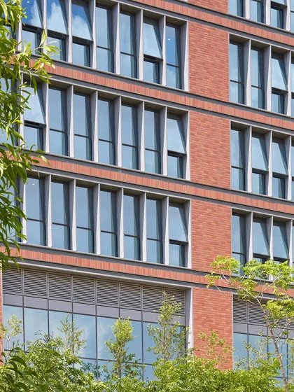 The facade of the Wipro Hyderabad Campus uses a combination of brick and glass, with deeply recessed windows that provide passive shading. This reduces solar heat gain and minimizes the need for mechanical cooling, contributing to the building's high energy performance.