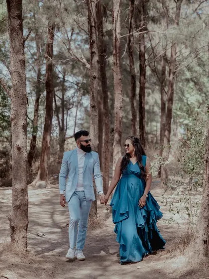 A couple walks hand-in-hand through a beautiful wooded area, creating a fairytale-like pre-wedding photograph.