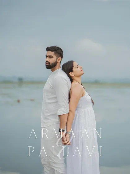 A serene portrait of a couple standing back-to-back and holding hands by the water in Kashmir.