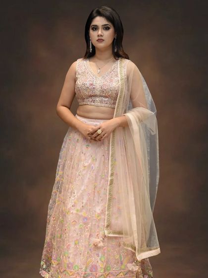 A full-length studio shot of the blush pink embroidered lehenga. This soft, romantic color is perfect for the bride who wants a fairytale wedding look.