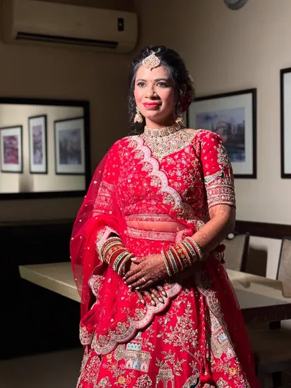 A full shot of the bride in her stunning red lehenga, looking happy and confident.
