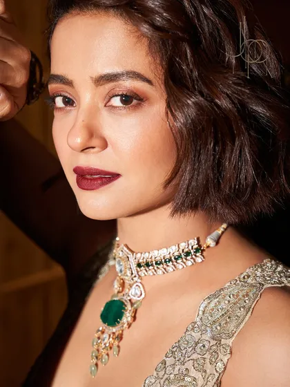 A close-up of the stunning Surveen Chawla, highlighting the exquisite detail of the emerald and polki necklace against her bold makeup.