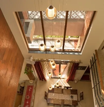 In the Reshma Residence, a large skylight transforms the central dining area into a dramatic, light-filled atrium. This top-down view shows how we engineer vertical spaces to create an open and airy atmosphere throughout the home, with pendant lights adding a warm glow.