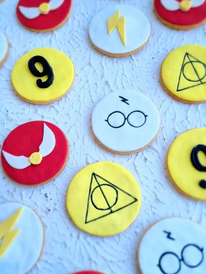 A close-up of the Harry Potter themed cookies, decorated with the Deathly Hallows symbol, glasses, and the golden snitch.
