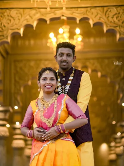 A grand indoor shot with the couple in vibrant traditional outfits. The ornate pillars and warm lighting create a royal ambiance for their pre-wedding photos.
