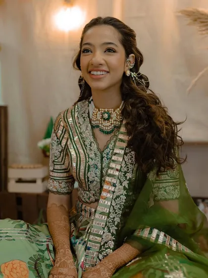 A portrait of the bride, her hair styled in a traditional half-updo that perfectly complements her green outfit.