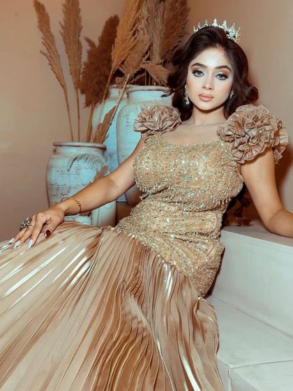 A model sitting elegantly in the golden princess gown, showcasing its rich texture and glamorous feel.