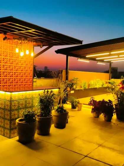 An inviting custom-built bar and pergola area at dusk in Palam Vihar, Gurgaon. The warm ambient lighting and functional design make this the perfect spot for evening entertainment and hosting guests.