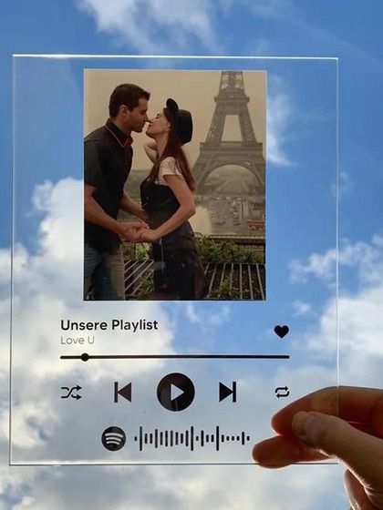 This image showcases the sleek, transparent design of the personalized music plaque. It looks almost invisible against the sky, highlighting the custom photo and song details.