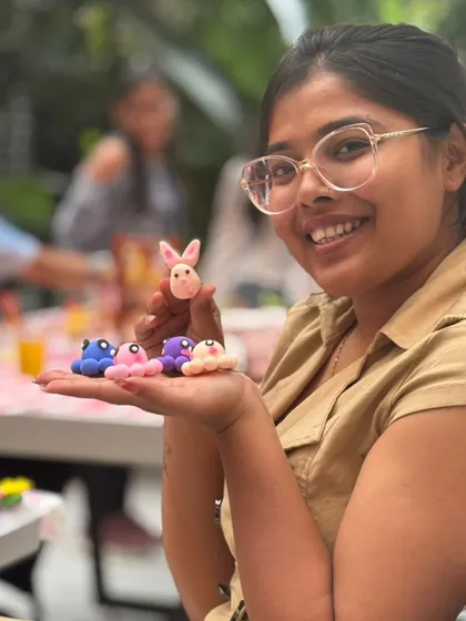 A participant smiles, showing off a whole family of tiny clay octopuses and a bunny she created. Our workshops are perfect for letting your imagination run wild with cute and whimsical creations.
