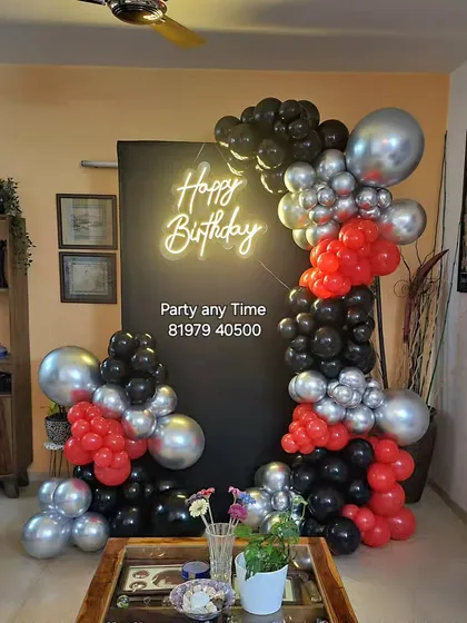 A trendy and unique design with a black backdrop and an organic arrangement of red, black, and silver balloons.