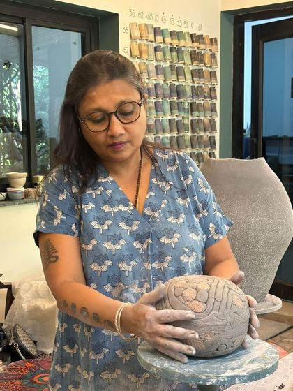 I love guiding students through their ambitious projects. Here, a student is carefully carving details into a large, spherical sculpture.