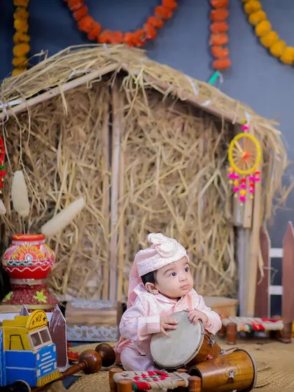 A sweet portrait of a baby sitting with a dhol, ready for his first Lohri celebration. The colorful dreamcatchers add a modern touch to the traditional setup.