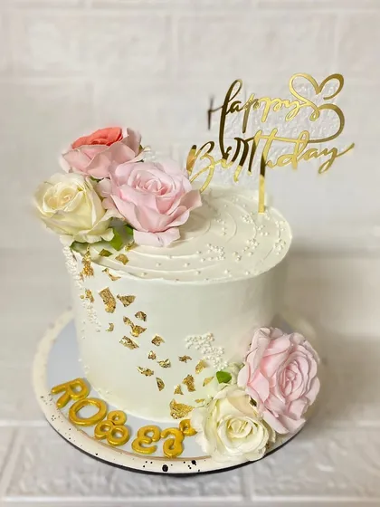 A side view of the elegant floral cake, showing the delicate gold leaf details.