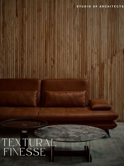 Textural finesse is showcased in this image, where a fluted wood wall provides a warm, tactile backdrop for a rich leather sofa and a cool marble coffee table.