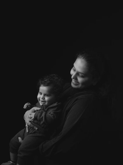 A tender black and white portrait of a mother holding her smiling baby, captured in a moment of quiet connection.