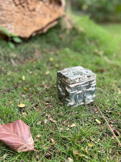 A finished stoneware Kurinuki box, resting in nature. The textures and form are a direct result of the carving process, making each piece entirely unique.