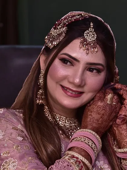 A smiling shot of the bride as she puts on her earrings, completing her stunning engagement look.