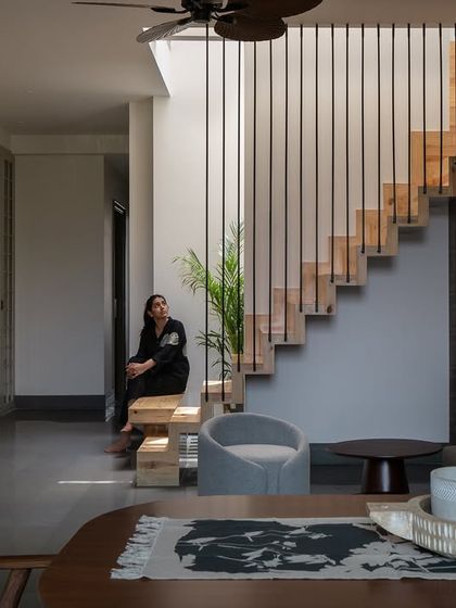 The pinewood staircase sits beside the light court, connecting the two floors without visual heaviness. A sculptural bench at its base creates a moment of pause within the flow of daily life.