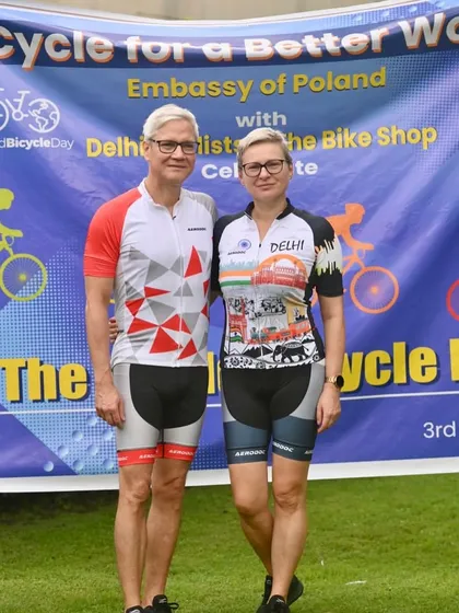 A couple in their cycling gear posing in front of the World Bicycle Day banner, showcasing the international spirit of the event.