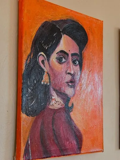 A close-up of one of my acrylic on canvas portraits. This piece features a woman with an introspective gaze, set against a warm orange background that highlights her features.
