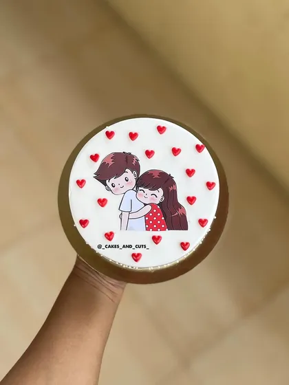 A cute cake featuring a cartoon couple, surrounded by little red hearts.