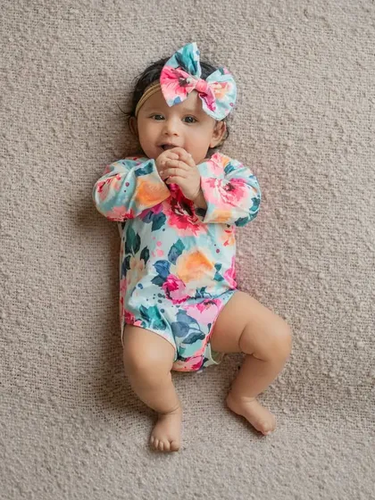 An adorable shot of a 3-month-old baby lying on a soft blanket. The simple, top-down angle and her direct gaze make for a sweet and engaging infant portrait.