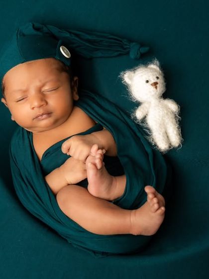 A classic moon prop setup. This portrait showcases a secure wrap in a rich teal color, with a tiny teddy bear prop to add a touch of sweetness.