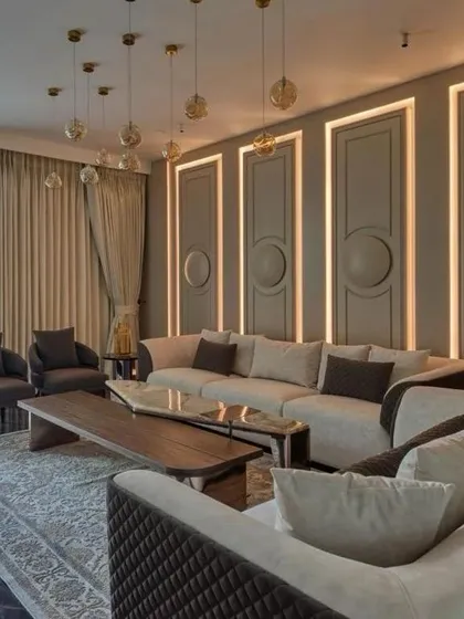 A masterclass in transitional interior design, this living room harmonizes comfort and style. The paneled walls with integrated lighting, plush sectional sofa, and natural wood coffee table create a refined yet welcoming escape.