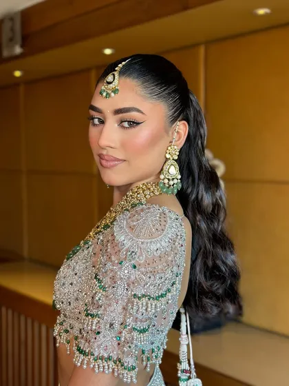 A side profile showcasing the sharp ponytail and the clean lines of the makeup. This look is for the bride who is confident and loves a modern aesthetic.